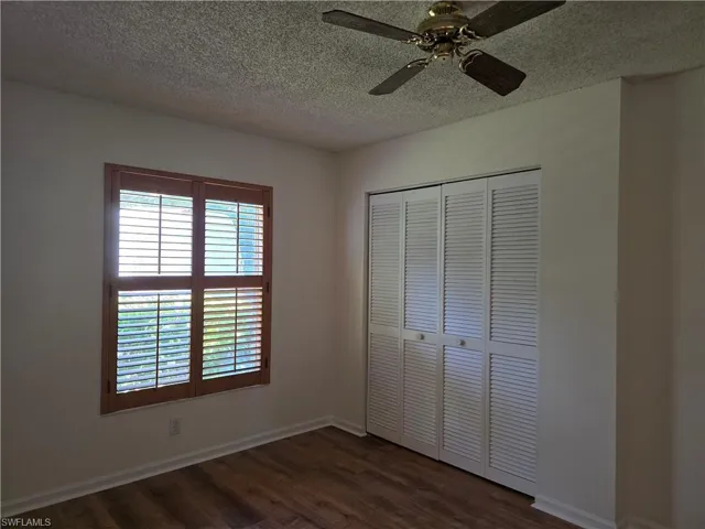 2nd bedroom featuring ceiling fan, dark hardwood / wood-style flooring, a closet, and a textured ceiling