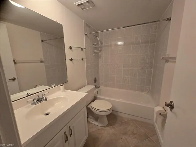 Full bathroom with tiled shower / bath combo, vanity, tile patterned floors, and toilet