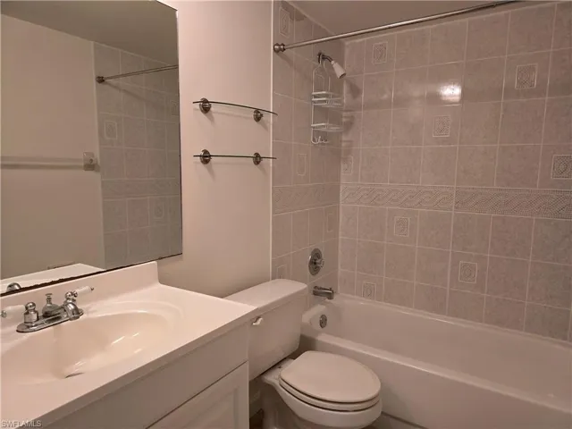 Full bathroom with vanity, tiled shower / bath combo, and toilet