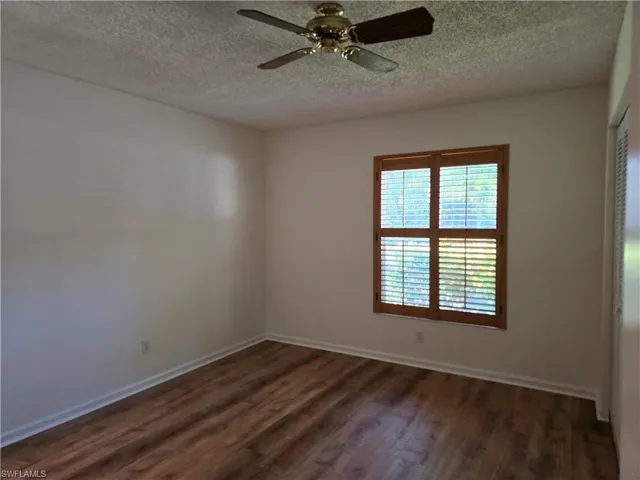 Master bedroom with dark hardwood / wood-style flooring, a textured ceiling, and ceiling fan