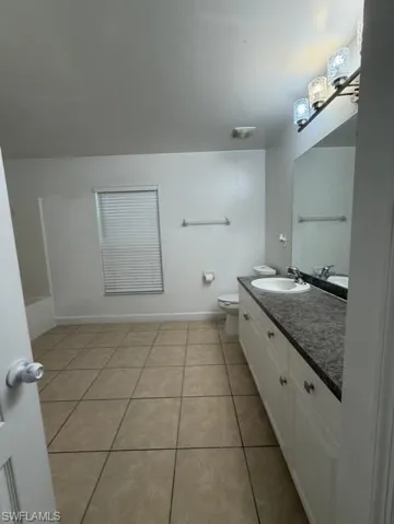 Bathroom featuring a double vanity with white cabinetry, a dark countertop, and a built-in sink