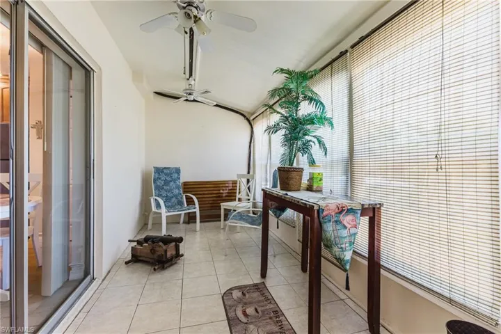 Enclosed patio featuring tile flooring and full-height windows with horizontal blinds