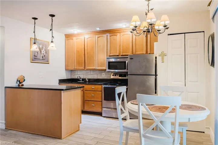 Kitchen featuring light wood cabinetry, dark countertops, and stainless steel appliances