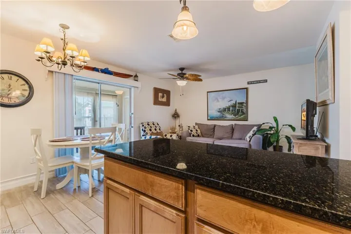 Kitchen island featuring a dark speckled countertop and light wood-finish cabinetry
