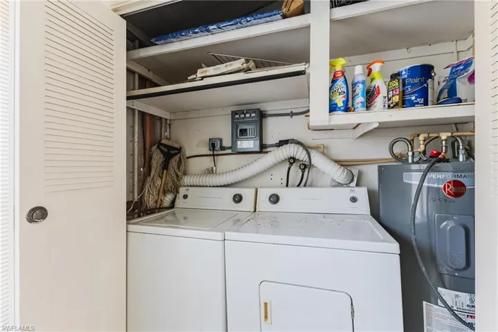 Dedicated utility closet featuring a washer and dryer setup, a hot water heater, and built-in shelving