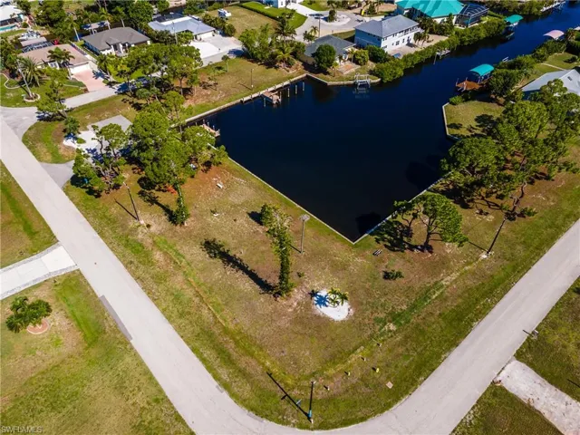 Waterfront lot featuring direct canal access, established trees, and paved road frontage