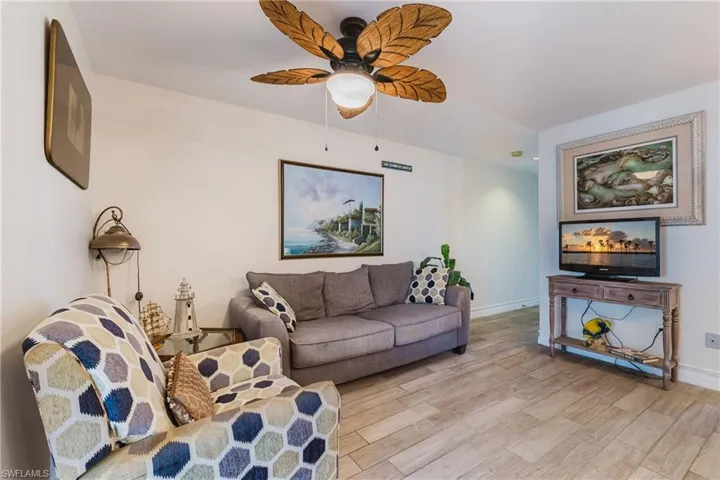 Spacious interior featuring light wood-finish flooring, a decorative ceiling fan with leaf-shaped blades, and white painted walls