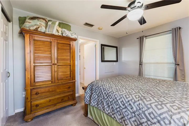 Carpeted room with a ceiling fan light fixture, light gray walls, and a window with blinds and gray drapes