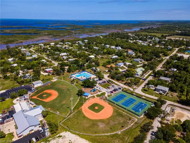 Aerial perspective showcasing a community with varied housing, two baseball fields, multiple tennis courts, and a swimming pool facility