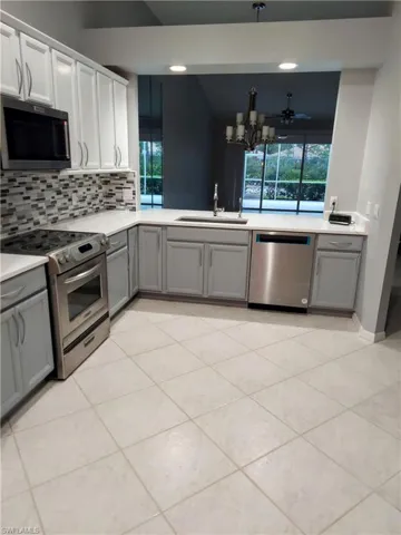 Kitchen featuring gray cabinets, appliances with stainless steel finishes, light countertops, and a sink