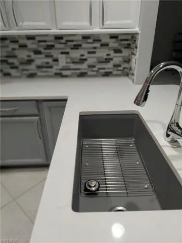Details featuring light countertops, a sink, white cabinetry, and decorative backsplash