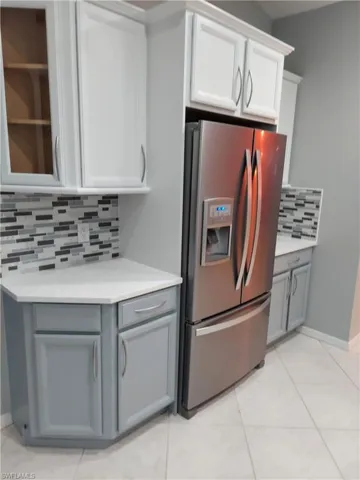 Kitchen featuring light countertops, stainless steel refrigerator with ice dispenser, gray cabinets, and white cabinets