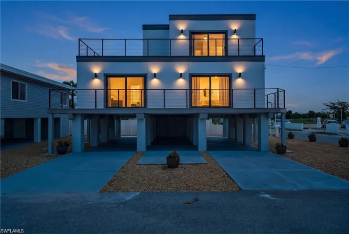 71 Mango Modern two-story exterior featuring multiple balconies with cable railings, integrated exterior lighting, and sliding glass doors
