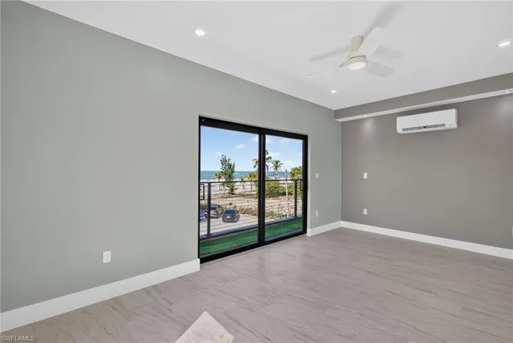 71 Mango Unit 2 Spacious bedroom featuring floor-to-ceiling sliding glass doors, coastal scenery, wood-finish flooring, a ceiling fan, and recessed lighting