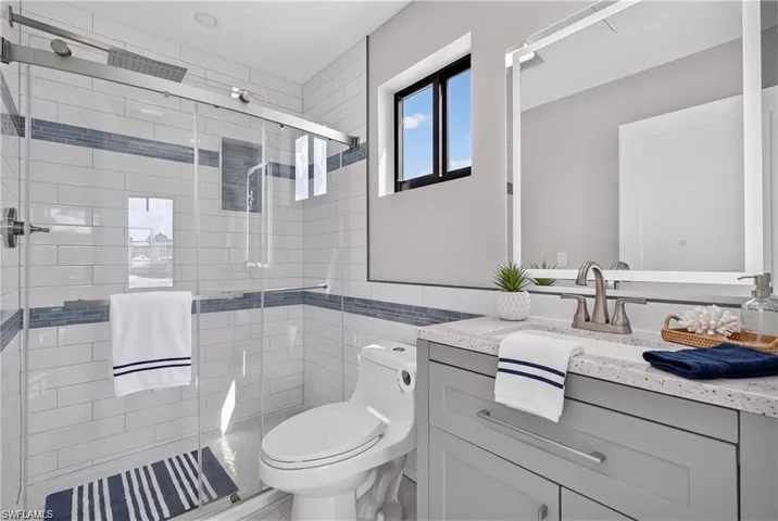71 Mango South Unit Primary Bathroom - Frameless glass shower enclosure with subway tile surround and integrated niche - VIRTUALLY STAGED