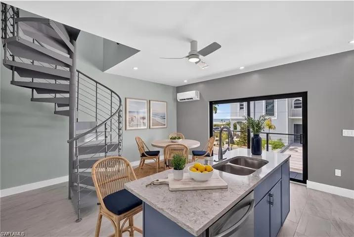 71 Mango North unit - Modern kitchen island with a double basin sink, gooseneck faucet, and light-toned countertop- VIRTUALLY STAGED