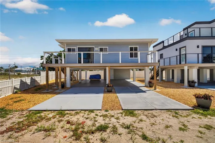 Elevated residence featuring light blue siding and a covered ground-level parking area