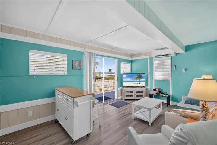 2101 Cottage Gulf facing Unit: Sliding glass door access to an outdoor deck, showcasing a bright interior with wood-finish flooring