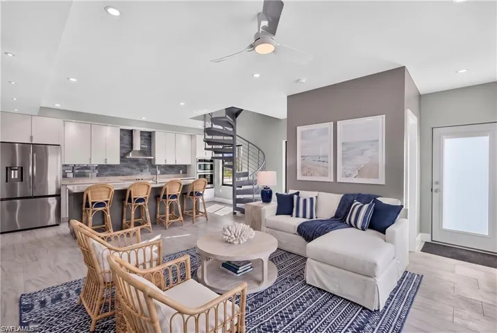 71 Mango south unit: Open-concept living space featuring a spiral staircase, recessed lighting, and a modern kitchen with stainless steel appliances and a breakfast bar - VIRTUALLY STAGED