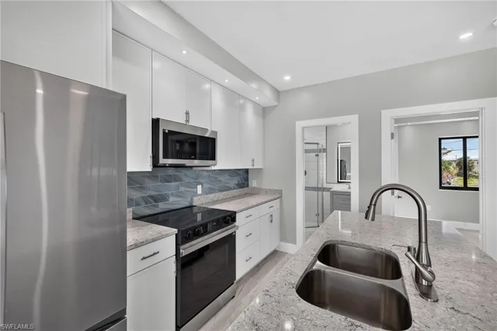 71 Mango North unit - Unfurnished Modern kitchen island with a double basin sink, gooseneck faucet, and light-toned countertop UNFURNISHED