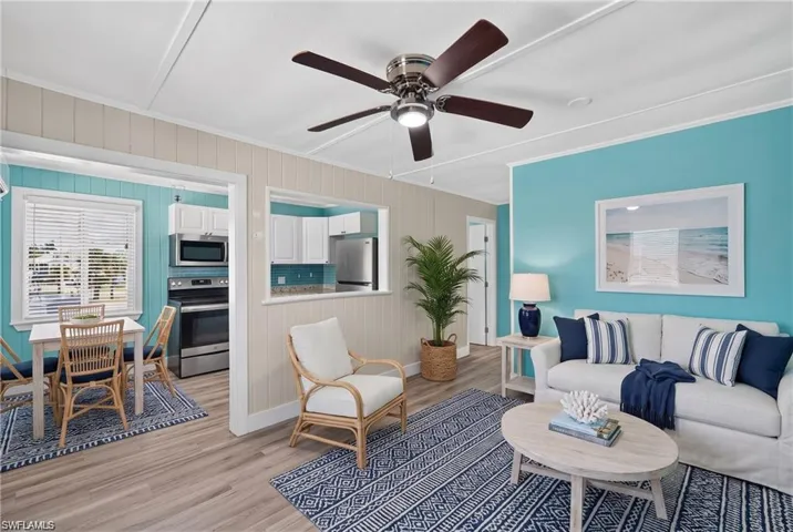 2101 Cottage North Unit - Wood-finish flooring throughout, ceiling fan with integrated lighting, kitchen pass-through, stainless steel appliances, and white cabinetry- VIRTUALLY STAGED