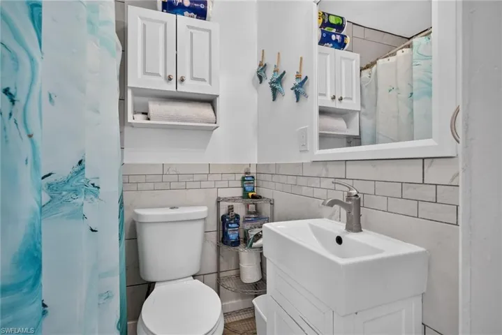 2101 Cottage Gulf facing Unit: White subway tile wainscoting, wall-mounted medicine cabinet with mirror, and a contemporary sink with a brushed nickel faucet