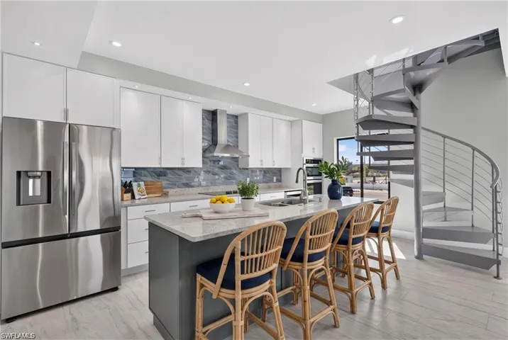71 Mango South Unit: Stainless steel appliances, built-in range hood, white flat-panel cabinetry, light-colored countertops, and a spiral staircase with metal railing - VIRTUALLY STAGED