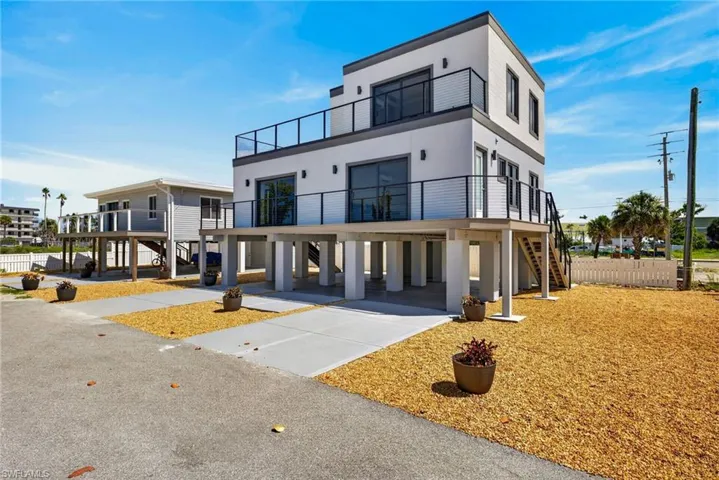 71 Mango Modern multi-story exterior with balconies featuring glass and metal railings, elevated on concrete pillars, multiple large windows, and an external staircase