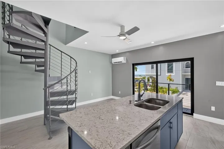 71 Mango Unit 2 Modern kitchen featuring white cabinetry, stainless steel appliances, light-toned countertops, a dual-basin stainless steel sink, and a blue tile backsplash