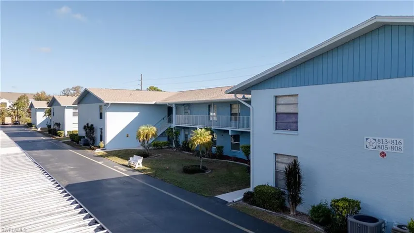 View of side of property with stairs, a lawn, stucco siding, a residential view, and a balcony