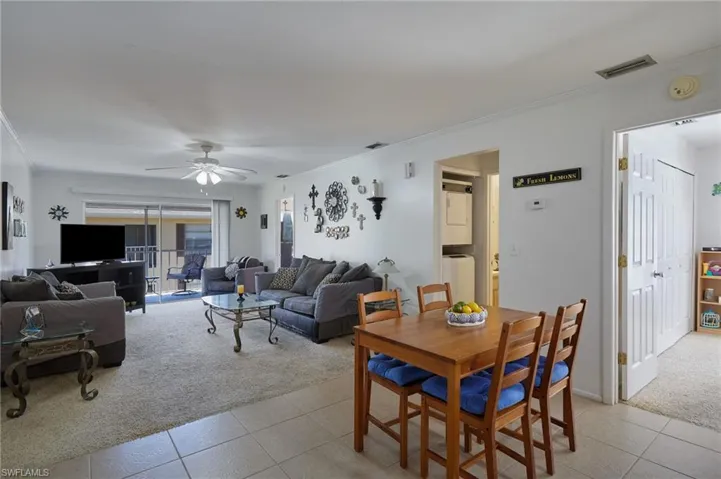 Dining area with ornamental molding, light carpet, ceiling fan, and light tile patterned floors