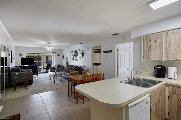 Kitchen with light brown cabinets, light countertops, a peninsula, dishwasher, and open floor plan