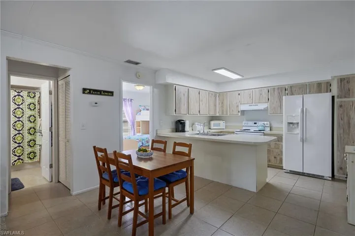 Kitchen featuring light countertops, white appliances, a peninsula, and light tile patterned flooring