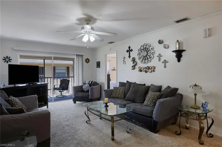 Living area featuring carpet floors, crown molding, and ceiling fan