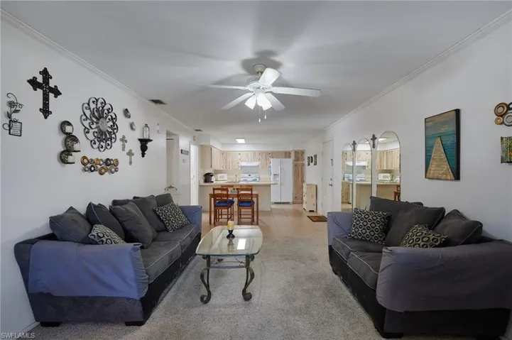 Living area with ornamental molding, light tile patterned floors, arched walkways, and a ceiling fan