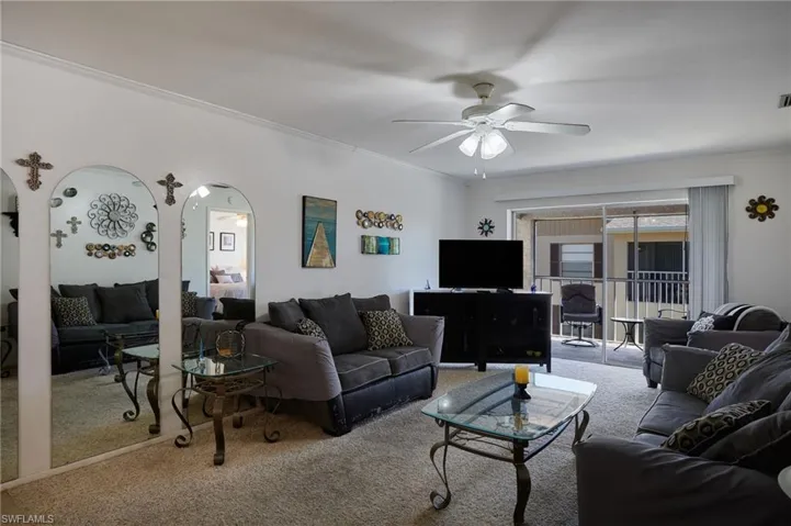 Carpeted living room featuring arched walkways, ornamental molding, and ceiling fan