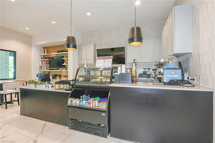 Kitchen with white cabinets, hanging light fixtures, and tile walls