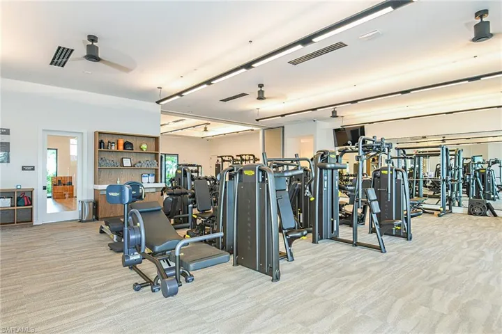 Gym with ceiling fan and light colored carpet