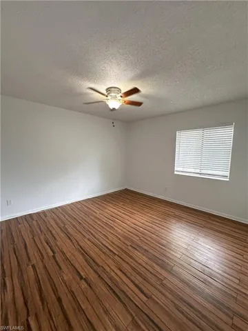 Spare room featuring dark wood finished floors, a textured ceiling, and ceiling fan