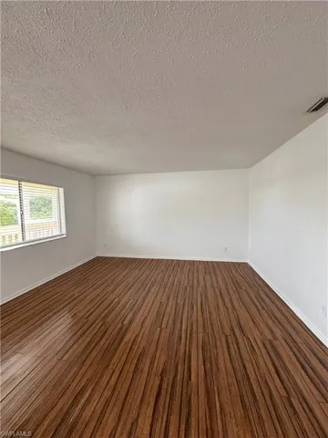 Spare room featuring dark wood finished floors and a textured ceiling