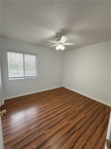 Unfurnished room with a textured ceiling, dark wood finished floors, and a ceiling fan