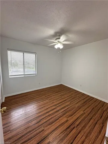 Spare room featuring a textured ceiling, dark wood-type flooring, and a ceiling fan