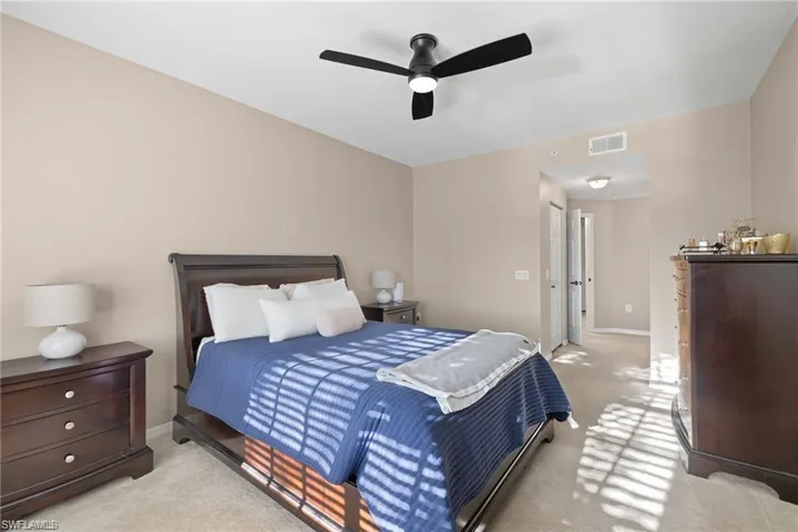 Bedroom with light colored carpet and a ceiling fan