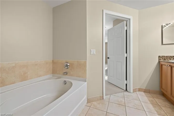 Bathroom with a bath, light tile patterned floors, and vanity