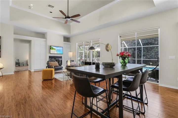 Dining area with wood finished floors, a tile fireplace, visible vents, and crown molding