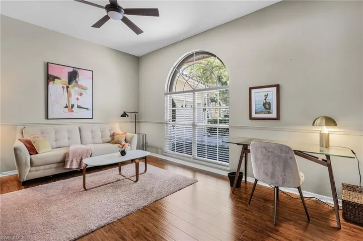 Living area featuring wood finished floors, a ceiling fan, and baseboards