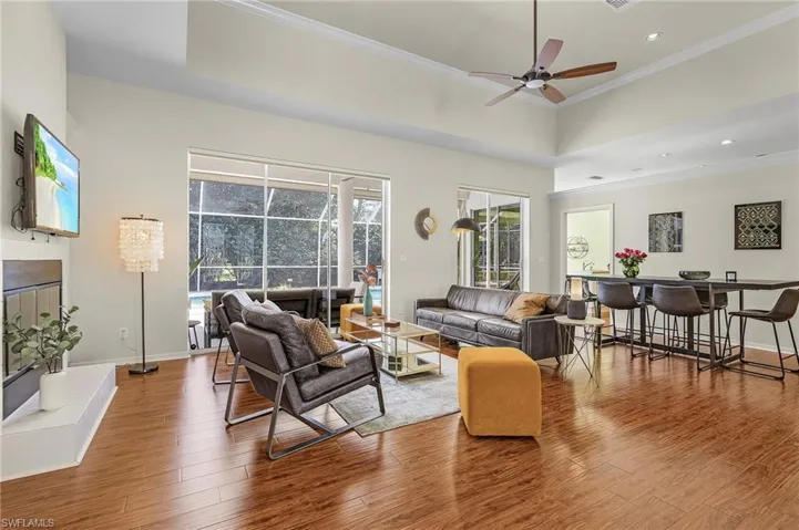 Living room with a ceiling fan, baseboards, ornamental molding, and wood finished floors