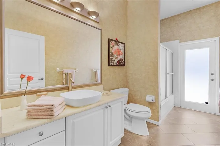 Bathroom with tile patterned floors, vanity, toilet, and an enclosed shower