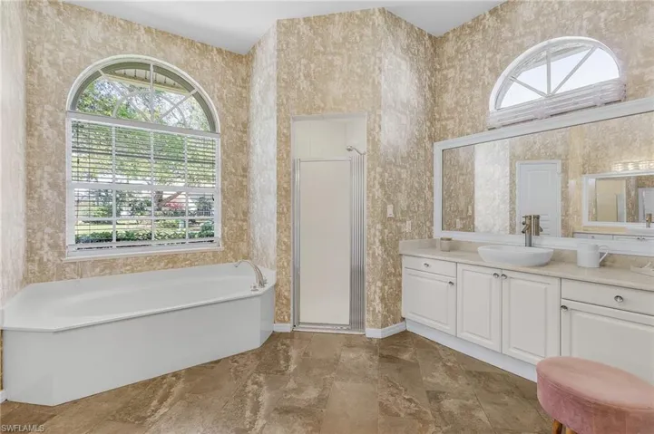 Bathroom featuring a garden tub, a shower stall, vanity, and wallpapered walls