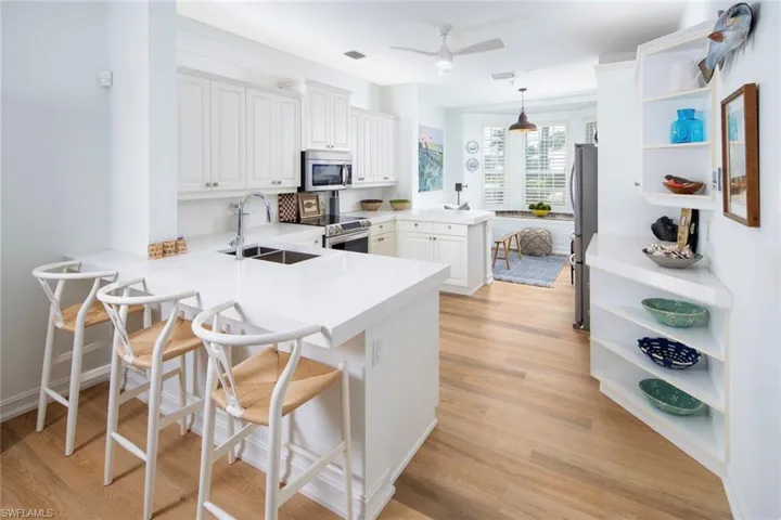 Kitchen featuring appliances with stainless steel finishes, a sink, open shelves, and a peninsula